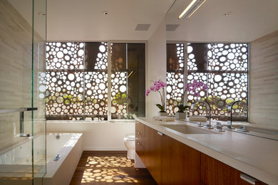 ロサンゼルスにある高級な中くらいなコンテンポラリースタイルのおしゃれなマスターバスルーム (フラットパネル扉のキャビネット、中間色木目調キャビネット、アンダーマウント型浴槽、アンダーカウンター洗面器、ライムストーンの洗面台、コーナー設置型シャワー、一体型トイレ	、ベージュのタイル、石タイル、白い壁、無垢フローリング) の写真