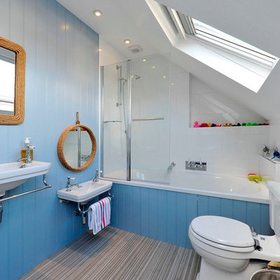 Example of a beach style white tile bathroom design in London with a wall-mount sink, a two-piece toilet and blue walls