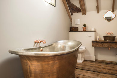 Réalisation d'une salle de bain principale champêtre en bois brun avec une baignoire indépendante, un mur blanc, parquet foncé, une vasque, un plan de toilette en bois, un sol marron et un plan de toilette marron.