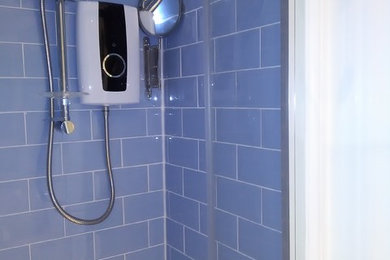 Photo of a small contemporary shower room bathroom in Hertfordshire with flat-panel cabinets, white cabinets, an alcove shower, a two-piece toilet, blue tiles, ceramic tiles, white walls, lino flooring and a console sink.