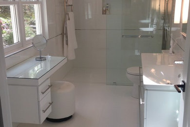 Mid-sized minimalist master white tile and ceramic tile cement tile floor and white floor bathroom photo in New York with flat-panel cabinets, white cabinets, a one-piece toilet, white walls, an integrated sink and solid surface countertops