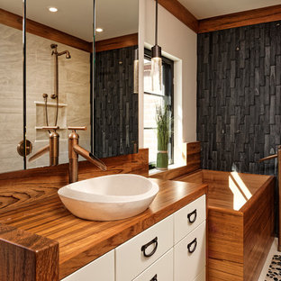 Inspiration for a mid-sized asian master bathroom in DC Metro with white cabinets, a japanese tub, porcelain floors, a vessel sink, wood benchtops, flat-panel cabinets, black tile, an open shower, a one-piece toilet, beige walls, stone tile, an open shower and brown benchtops.