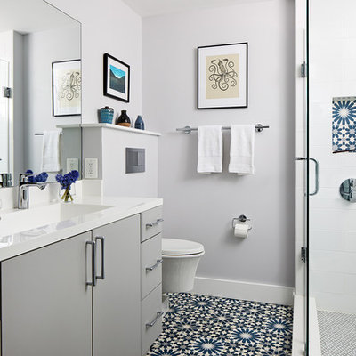 Corner shower - mid-sized contemporary 3/4 white tile blue floor corner shower idea in DC Metro with flat-panel cabinets, gray cabinets, a wall-mount toilet, gray walls, a hinged shower door, white countertops and an integrated sink