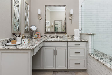 Mid-sized cottage chic master white tile and ceramic tile brown floor corner shower photo in Dallas with raised-panel cabinets, beige cabinets, brown walls, an undermount sink, marble countertops, a hinged shower door and multicolored countertops