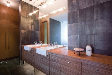 Foto på ett mellanstort funkis en-suite badrum, med släta luckor, skåp i mellenmörkt trä, ett platsbyggt badkar, grå kakel, stenkakel, vita väggar, klinkergolv i porslin, ett fristående handfat och bänkskiva i akrylsten