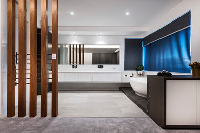 Ejemplo de cuarto de baño moderno con armarios con paneles lisos, puertas de armario blancas, bañera exenta, paredes blancas, suelo gris y encimeras blancas