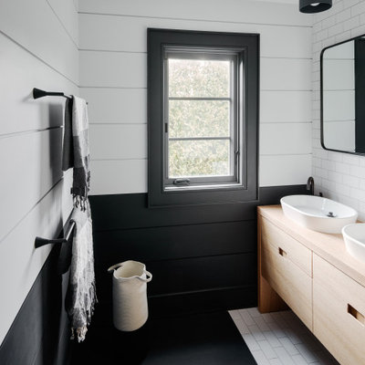 Bathroom - contemporary white tile and subway tile black floor bathroom idea in New York with flat-panel cabinets, light wood cabinets, multicolored walls, a vessel sink and wood countertops