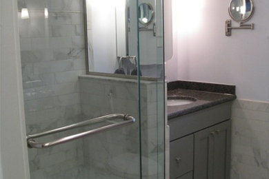 Kleines Klassisches Badezimmer En Suite mit flächenbündigen Schrankfronten, grauen Schränken, Eckdusche, grauen Fliesen, Porzellanfliesen und Porzellan-Bodenfliesen in New York