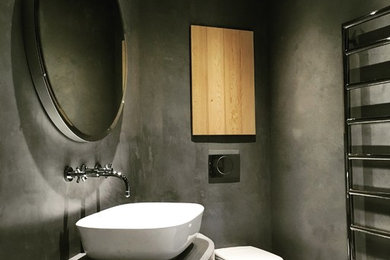 他の地域にある広いコンテンポラリースタイルのおしゃれなマスターバスルーム (淡色木目調キャビネット、壁掛け式トイレ、グレーのタイル、グレーの壁) の写真