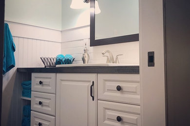 ボイシにある中くらいなトラディショナルスタイルのおしゃれなバスルーム (浴槽なし) (レイズドパネル扉のキャビネット、白いキャビネット、白いタイル、サブウェイタイル、タイルの洗面台、黒い洗面カウンター、アルコーブ型シャワー、青い壁、濃色無垢フローリング、オーバーカウンターシンク、シャワーカーテン) の写真