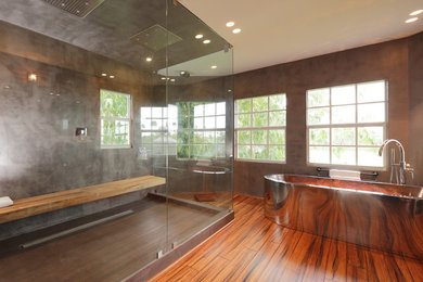 Imagen de cuarto de baño principal actual extra grande con bañera exenta, ducha doble, paredes grises y suelo de madera en tonos medios