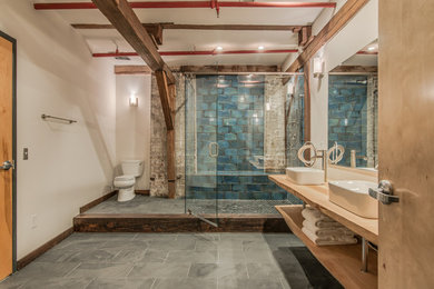Example of a large urban master blue tile and ceramic tile slate floor walk-in shower design in Nashville with a vessel sink, open cabinets, light wood cabinets, wood countertops and white walls