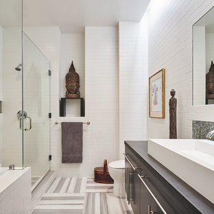 Example of a master white tile multicolored floor corner shower design in New York with flat-panel cabinets, gray cabinets, white walls, a vessel sink, a hinged shower door and gray countertops