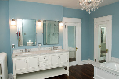 Diseño de cuarto de baño tradicional de tamaño medio con encimera de granito, bañera esquinera, baldosas y/o azulejos blancos y suelo de madera oscura