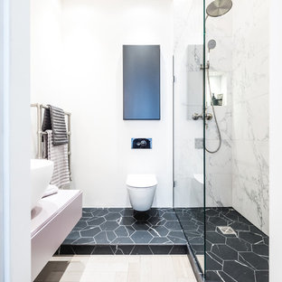 Photo of a medium sized contemporary bathroom in London with flat-panel cabinets, white cabinets, an alcove bath, a wall mounted toilet, white tiles, marble tiles, white walls, a vessel sink, multi-coloured floors, an open shower, white worktops and a wall niche.