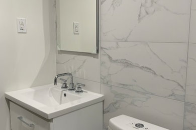 ニューヨークにあるトランジショナルスタイルのおしゃれな浴室 (フラットパネル扉のキャビネット、白いキャビネット、分離型トイレ、白いタイル、大理石タイル、白い壁、一体型シンク、白い床、白い洗面カウンター) の写真