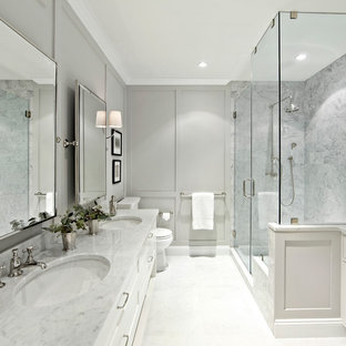 Inspiration for a large traditional ensuite bathroom in New York with shaker cabinets, white cabinets, white tiles, stone tiles, grey walls, marble worktops, a corner shower and a hinged door.