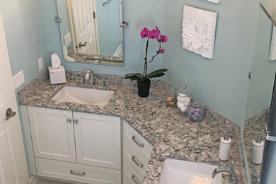 This is an example of a medium sized traditional ensuite bathroom in Other with recessed-panel cabinets, white cabinets, an alcove shower, a two-piece toilet, white tiles, porcelain tiles, blue walls, porcelain flooring, a submerged sink, engineered stone worktops, white floors and a sliding door.