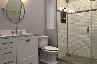ニューヨークにある中くらいなトランジショナルスタイルのおしゃれなバスルーム (浴槽なし) (シェーカースタイル扉のキャビネット、白いキャビネット、アルコーブ型シャワー、分離型トイレ、白いタイル、サブウェイタイル、グレーの壁、磁器タイルの床、アンダーカウンター洗面器、グレーの床、開き戸のシャワー) の写真