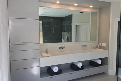 Cette image montre une salle de bain principale design de taille moyenne avec un placard à porte plane, des portes de placard grises, un lavabo suspendu, un plan de toilette en béton et un mur blanc.