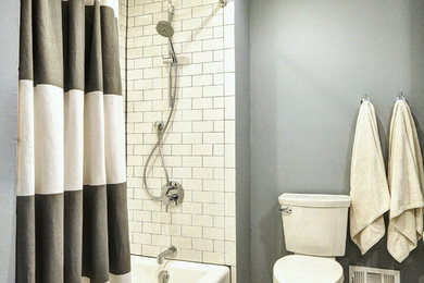 Bild på ett mellanstort funkis badrum, med ett integrerad handfat, släta luckor, skåp i mörkt trä, bänkskiva i akrylsten, ett badkar i en alkov, en toalettstol med separat cisternkåpa, vit kakel, tunnelbanekakel, blå väggar och klinkergolv i porslin