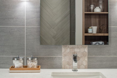 Example of a mid-sized trendy master white tile and porcelain tile porcelain tile walk-in shower design in Omaha with flat-panel cabinets, medium tone wood cabinets, a one-piece toilet, gray walls, an undermount sink and quartz countertops
