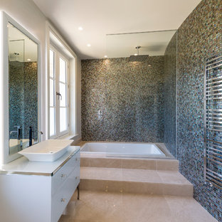 This is an example of a medium sized traditional bathroom in Surrey with flat-panel cabinets, white cabinets, a japanese bath, a shower/bath combination, blue tiles, mosaic tiles, blue walls, a vessel sink, beige floors, an open shower and white worktops.