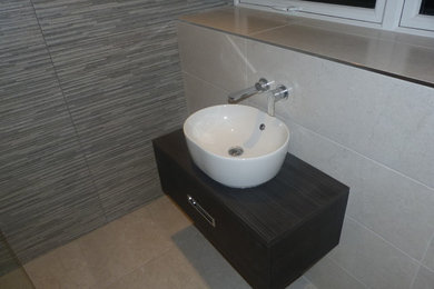 Photo of a medium sized contemporary family bathroom in Cheshire with freestanding cabinets, brown cabinets, an alcove shower, a wall mounted toilet, beige tiles, ceramic tiles, grey walls, porcelain flooring, a vessel sink, laminate worktops, beige floors and an open shower.