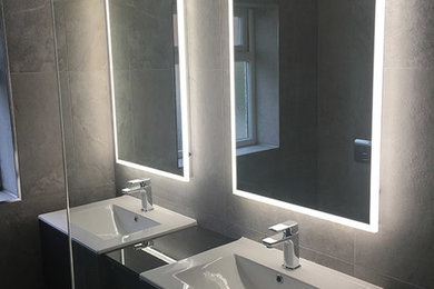 This is an example of a small contemporary bathroom in London with a wall mounted toilet, grey tiles, ceramic tiles, grey walls, ceramic flooring and a wall-mounted sink.
