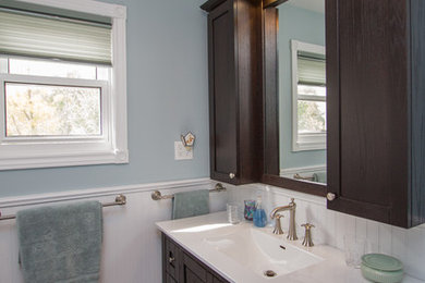 Foto på ett mellanstort vintage en-suite badrum, med möbel-liknande, skåp i mörkt trä, en dusch i en alkov, en toalettstol med separat cisternkåpa, vit kakel, porslinskakel, blå väggar, vinylgolv, ett integrerad handfat och marmorbänkskiva