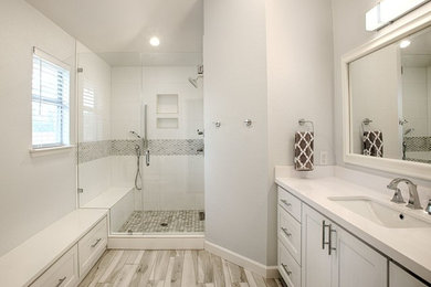 Foto de cuarto de baño principal tradicional de tamaño medio con armarios estilo shaker, puertas de armario blancas, ducha empotrada, baldosas y/o azulejos grises, paredes blancas, lavabo bajoencimera y encimera de cuarzo compacto