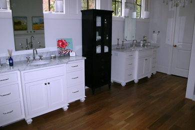 Modelo de cuarto de baño principal contemporáneo grande con armarios con paneles lisos, puertas de armario blancas, paredes amarillas, suelo de madera clara, lavabo bajoencimera y encimera de mármol
