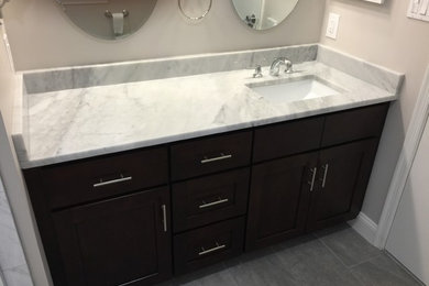 Inspiration for a modern laminate floor bathroom remodel with flat-panel cabinets, black cabinets, beige walls, a drop-in sink and marble countertops
