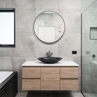 Inspiration för mellanstora moderna vitt en-suite badrum, med skåp i ljust trä, ett badkar i en alkov, grå kakel, svart kakel, porslinskakel, grå väggar, klinkergolv i porslin, ett konsol handfat, bänkskiva i akrylsten, grått golv, med dusch som är öppen, släta luckor och en dusch i en alkov