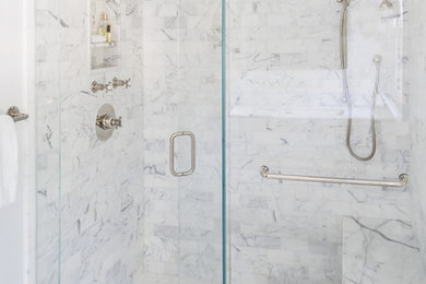 Idée de décoration pour une douche en alcôve tradition avec un placard à porte shaker, des portes de placard blanches, WC à poser, un carrelage blanc, un carrelage de pierre, un mur blanc, un sol en marbre, un lavabo encastré et un plan de toilette en marbre.