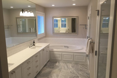 Inspiration for a mid-sized transitional master white tile and subway tile marble floor drop-in bathtub remodel in Portland with raised-panel cabinets, white cabinets, gray walls, an undermount sink and solid surface countertops