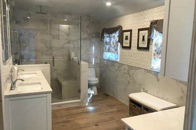Inspiration for a timeless white tile and porcelain tile porcelain tile and brown floor bathroom remodel in Philadelphia with shaker cabinets, white cabinets, a one-piece toilet, an undermount sink, quartz countertops and a hinged shower door