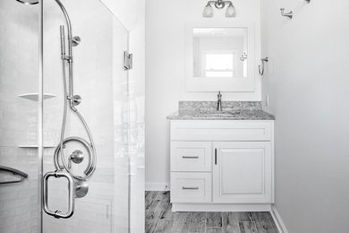 Inspiration for a large contemporary master white tile and ceramic tile medium tone wood floor and gray floor alcove shower remodel in New York with raised-panel cabinets, white cabinets, a two-piece toilet, white walls, a drop-in sink, granite countertops and a hinged shower door