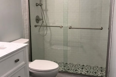 Inredning av ett klassiskt litet badrum, med skåp i shakerstil, vita skåp, en toalettstol med separat cisternkåpa, grå kakel, porslinskakel, grå väggar, klinkergolv i porslin, ett undermonterad handfat, marmorbänkskiva, grått golv och dusch med skjutdörr