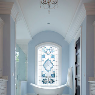 This is an example of a large traditional ensuite bathroom in Houston with a claw-foot bath, recessed-panel cabinets, white cabinets, an alcove shower, white tiles, blue walls, marble flooring, marble worktops, white floors, a hinged door and white worktops.