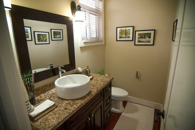 Imagen de cuarto de baño clásico de tamaño medio con armarios con paneles con relieve, puertas de armario de madera oscura, encimera de granito, paredes amarillas y suelo de madera oscura