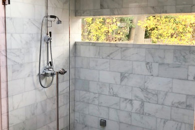 Inspiration for a mid-sized timeless master gray tile and marble tile porcelain tile and gray floor walk-in shower remodel in New York with shaker cabinets, white cabinets, a two-piece toilet, white walls, an undermount sink, quartz countertops, a hinged shower door and white countertops