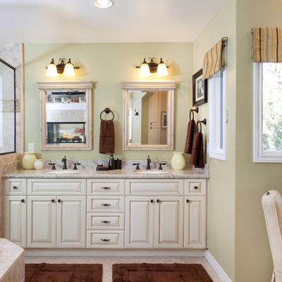 Bathroom - mid-sized traditional master porcelain tile ceramic tile and beige floor bathroom idea in San Diego with raised-panel cabinets, white cabinets, solid surface countertops, an undermount sink, beige walls and a hinged shower door