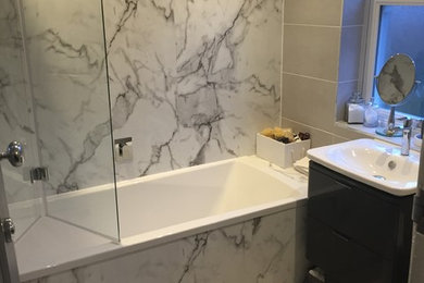 Small contemporary family bathroom in Other with flat-panel cabinets, grey cabinets, a built-in bath, a shower/bath combination, a one-piece toilet, grey tiles, porcelain tiles, grey walls, porcelain flooring and a console sink.