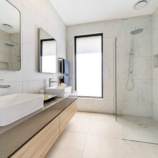 This is an example of a mid-sized contemporary master bathroom in Melbourne with furniture-like cabinets, light wood cabinets, a freestanding tub, a corner shower, a one-piece toilet, white tile, ceramic tile, white walls, ceramic floors, engineered quartz benchtops, grey floor, an open shower and grey benchtops.
