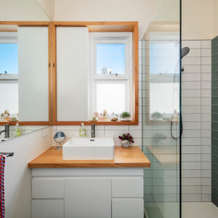 Mid-sized contemporary 3/4 bathroom in Melbourne with recessed-panel cabinets, white cabinets, an open shower, a wall-mount toilet, green tile, ceramic tile, multi-coloured walls, ceramic floors, a trough sink, wood benchtops, multi-coloured floor, an open shower, white benchtops, a single vanity and a floating vanity.