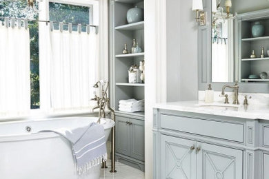 На фото: большая главная ванная комната в классическом стиле с фасадами островного типа, синими фасадами, отдельно стоящей ванной, унитазом-моноблоком, серой плиткой, серыми стенами, мраморным полом, врезной раковиной, мраморной столешницей, белым полом и белой столешницей
