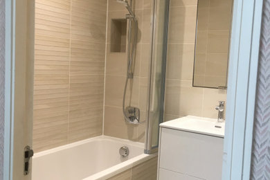 Design ideas for a small classic ensuite bathroom in London with flat-panel cabinets, beige cabinets, a walk-in shower, a wall mounted toilet, beige tiles, porcelain tiles, beige walls, porcelain flooring, a built-in sink, tiled worktops, beige floors and beige worktops.