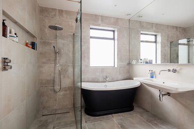 Medium sized contemporary wet room bathroom in London with a freestanding bath, a wall-mounted sink and grey floors.