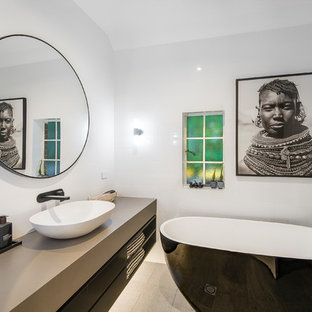 Photo of a mid-sized contemporary master bathroom in Brisbane with flat-panel cabinets, ceramic tile, white walls, a vessel sink, marble benchtops, black cabinets, a freestanding tub, white tile, beige floor and beige benchtops.